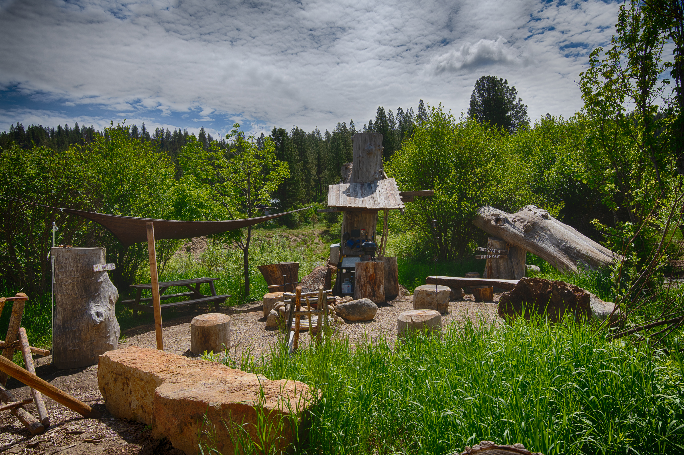 Teepee campground with large firepit and custom log benches next to the river in Garden Valley, Idaho Campsite for rent.