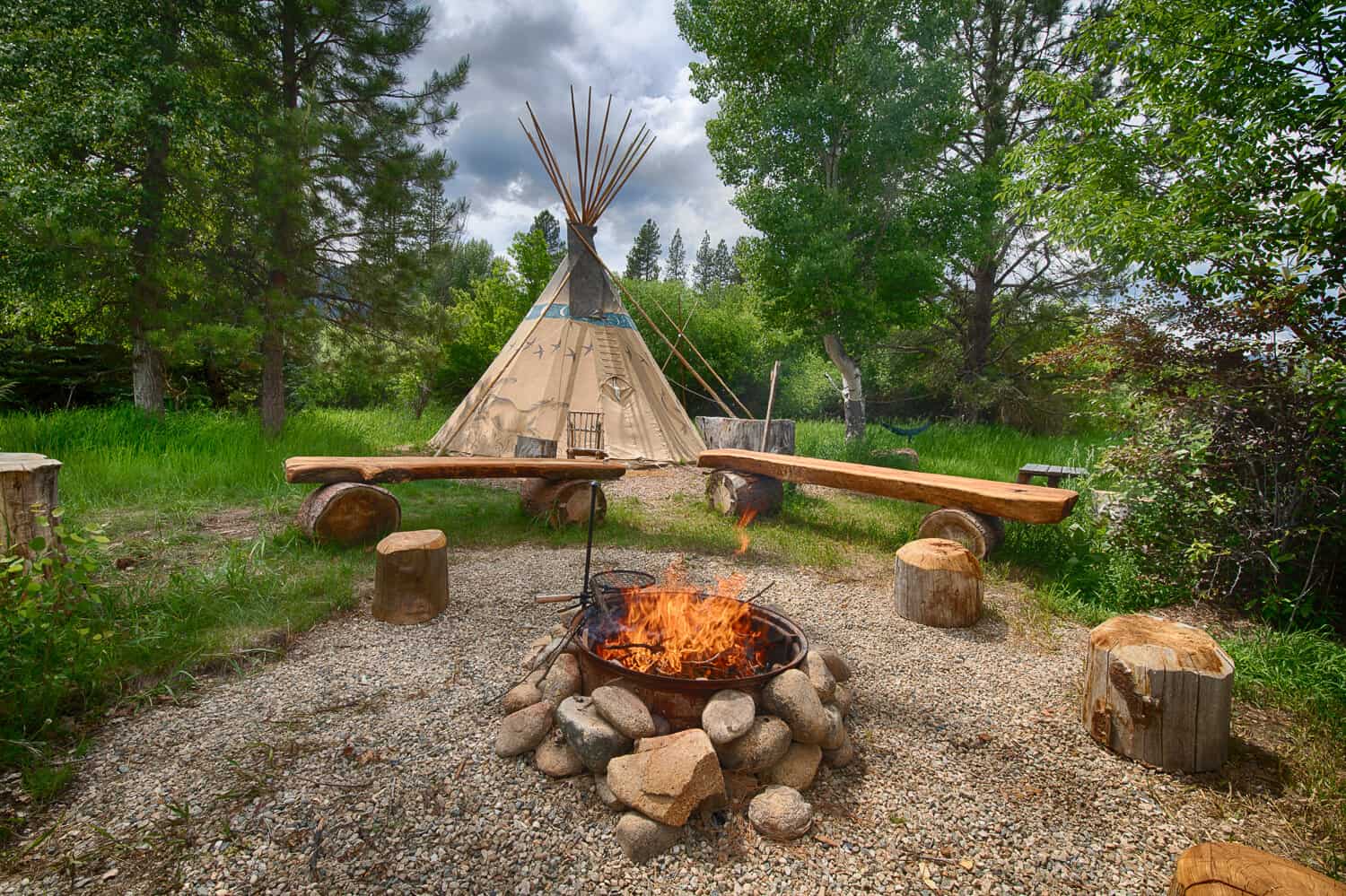 Authentic tipi in a teepee campground in Garden Valley, Idaho. Campfire burning in foreground at the firepit.
